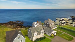 A coastal residential area with houses, a clear view of the sea, and a rocky shoreline. - Wright by the Sea For 10! (York Beach)