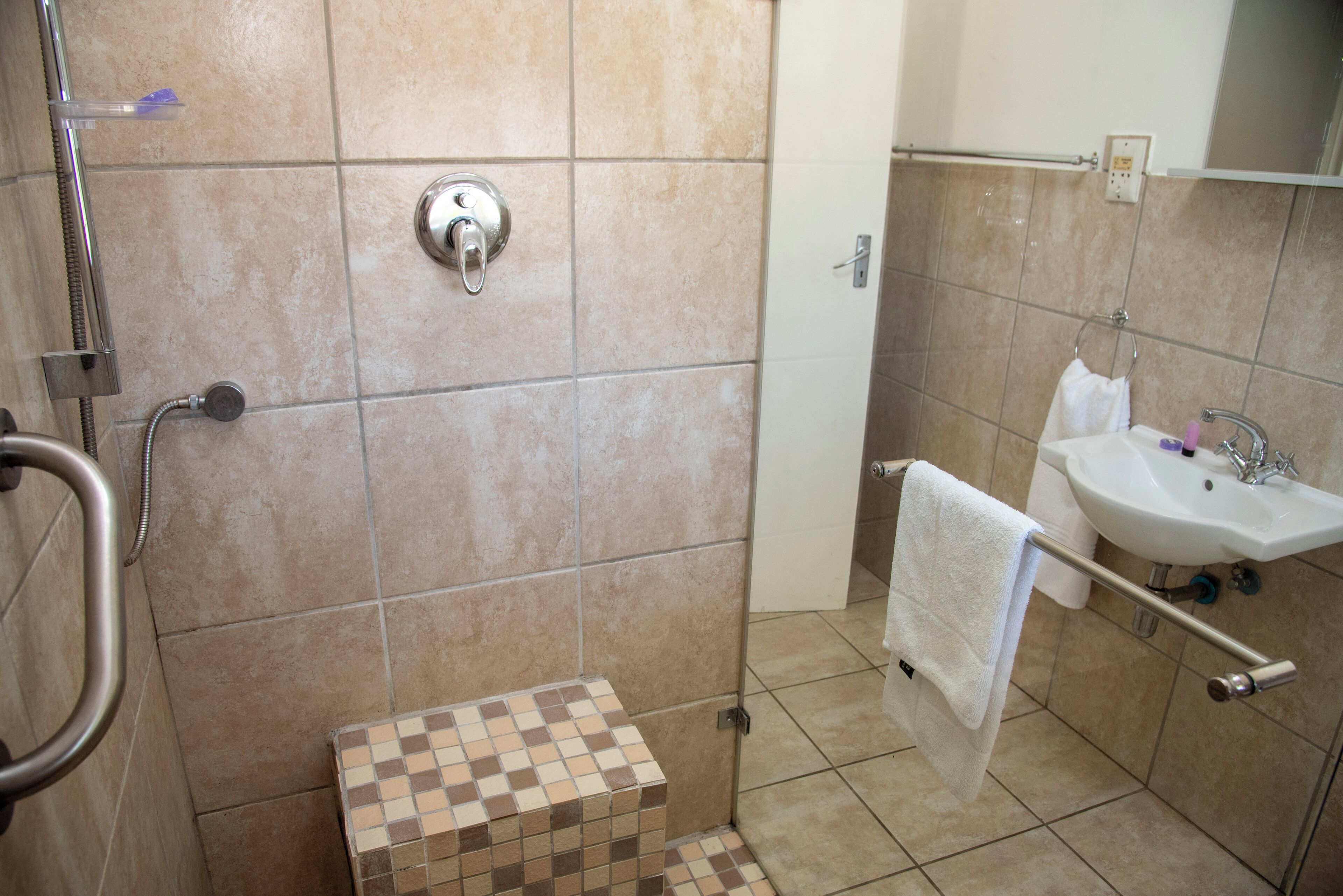 Un baño con ducha, lavamanos y piso de baldosas.