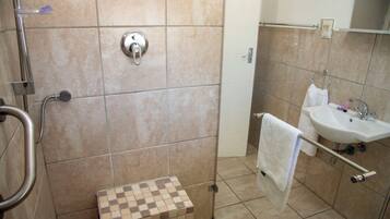 Un baño con ducha, lavamanos y piso de baldosas.