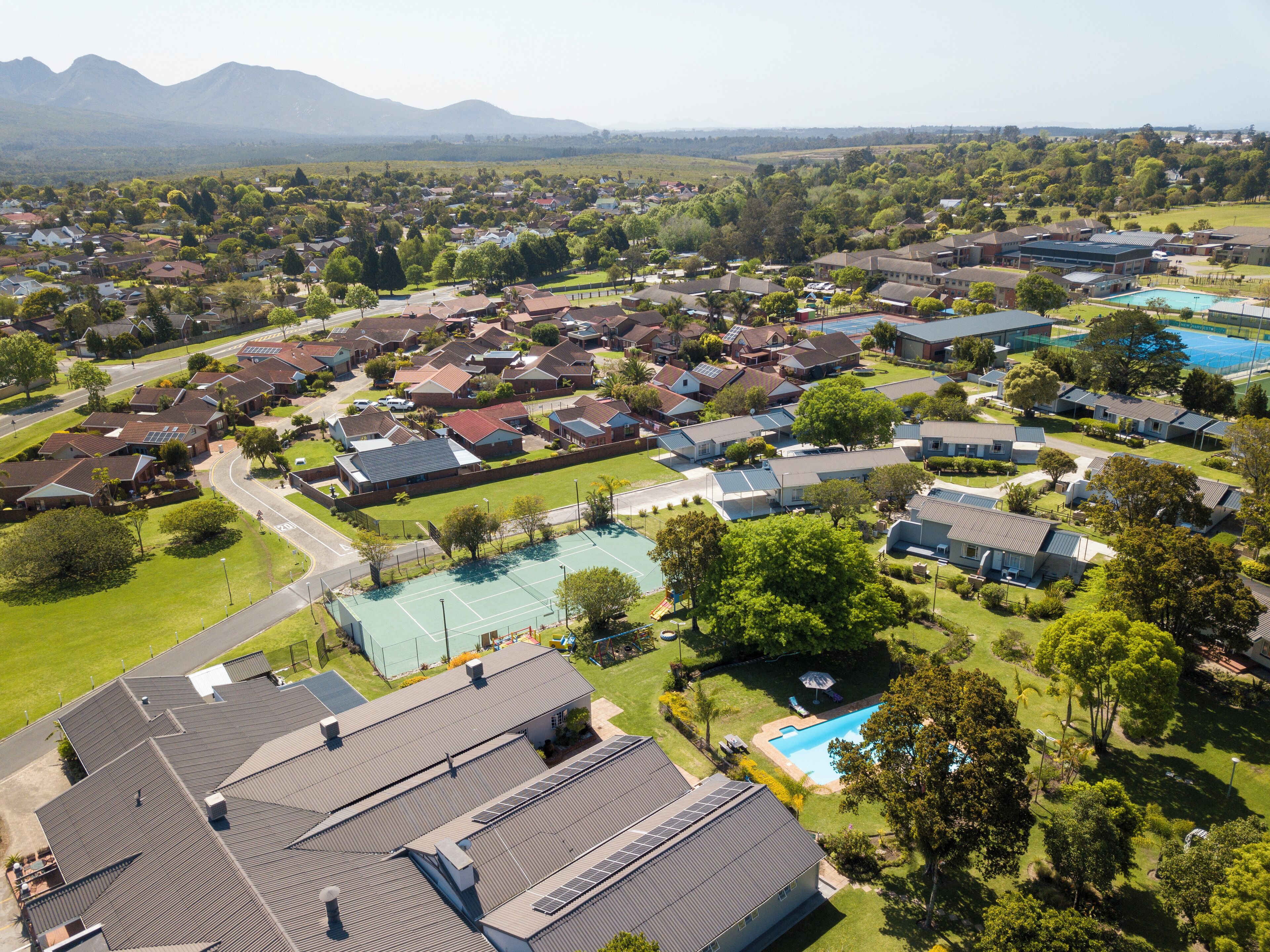 Zona residenziale con case, piscina e campo da tennis.