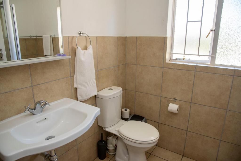 A bathroom with a sink, toilet, and a window.