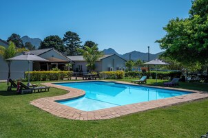 Una piscina al aire libre, sombrillas, tumbonas