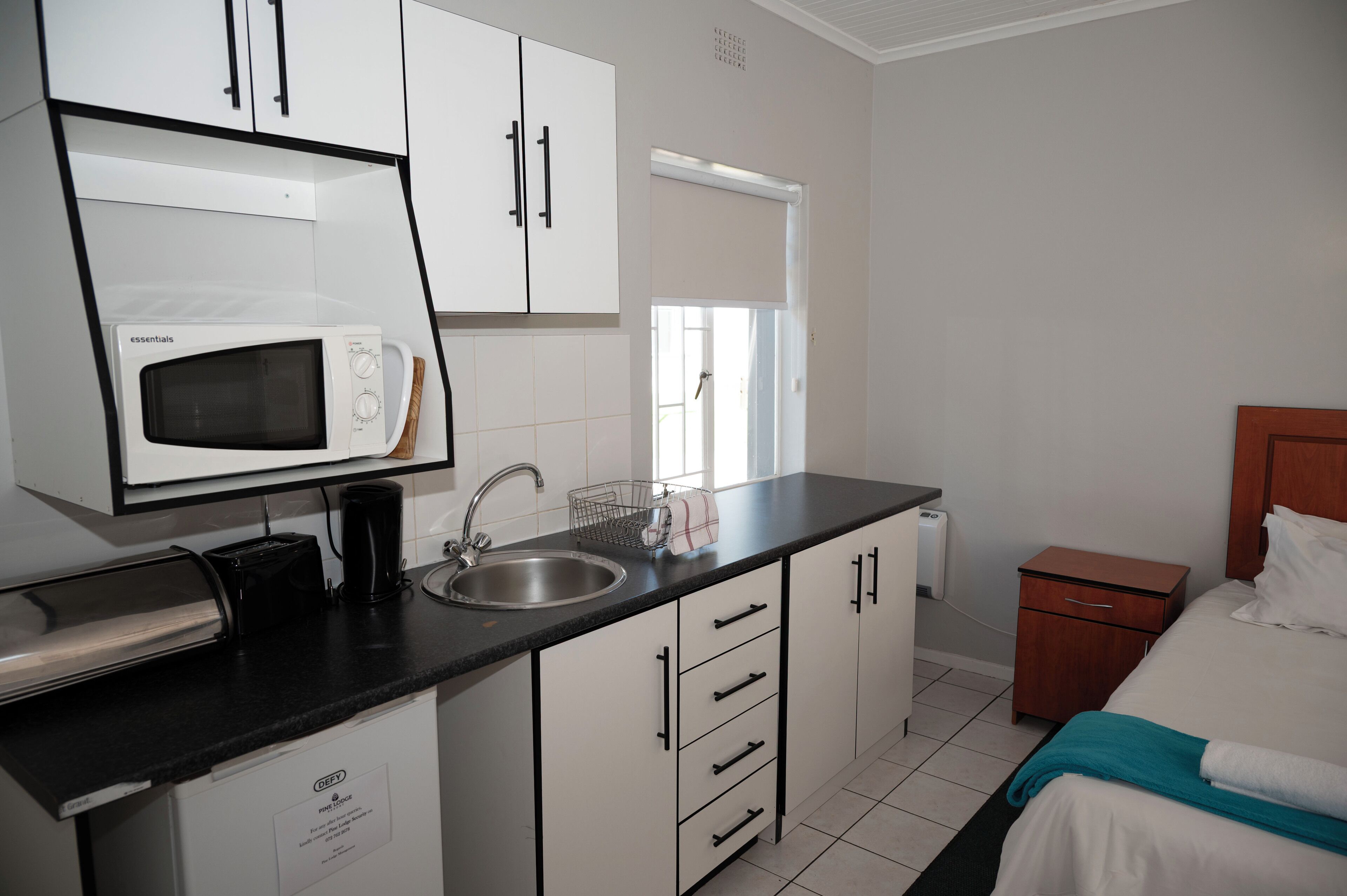 A compact kitchenette with a microwave, sink, and storage cabinets.