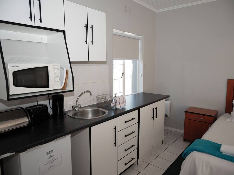 Una kitchenette compacta con microondas, pileta y alacenas.