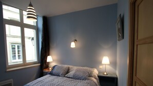 A bedroom with a bed, two bedside lamps, a window, and a door.