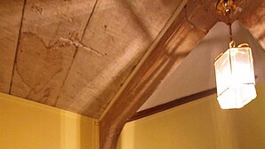 A staircase with a wooden handrail and a black metal railing, leading to a landing with a light fixture.