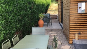 A patio with a green table and chairs, surrounded by a wooden fence and a well-maintained hedge.