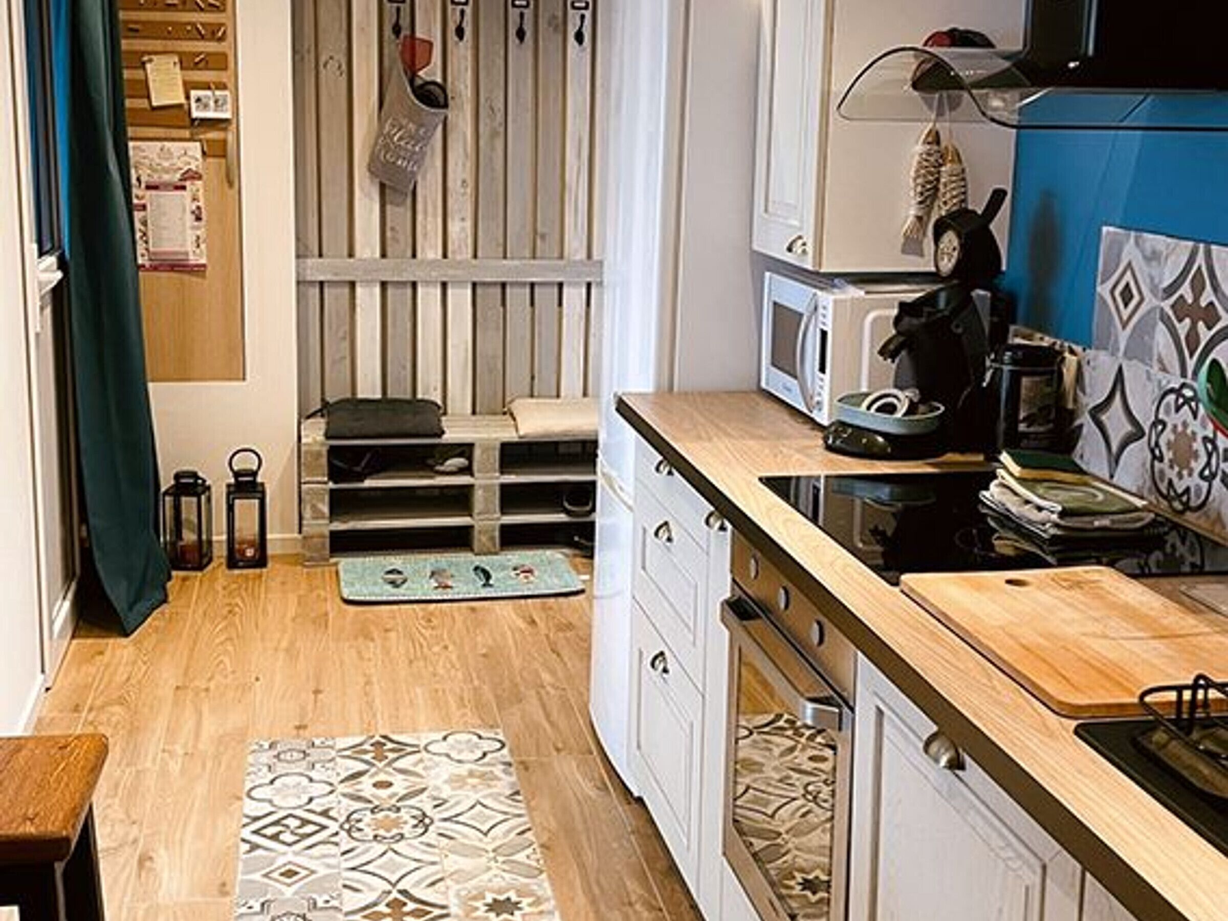 A compact kitchen with a microwave, stove, and wooden countertop.