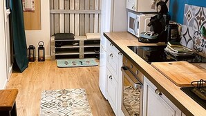 A compact kitchen with a microwave, stove, and wooden countertop.