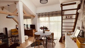 A cozy living room with a dining area, a staircase, and a kitchen.