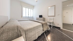 Une chambre à coucher comprenant un lit, une chaise, une commode, un miroir et un ventilateur de plafond.