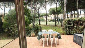 Een buitenpatio met een tafel en stoelen, omringd door groen en bomen.