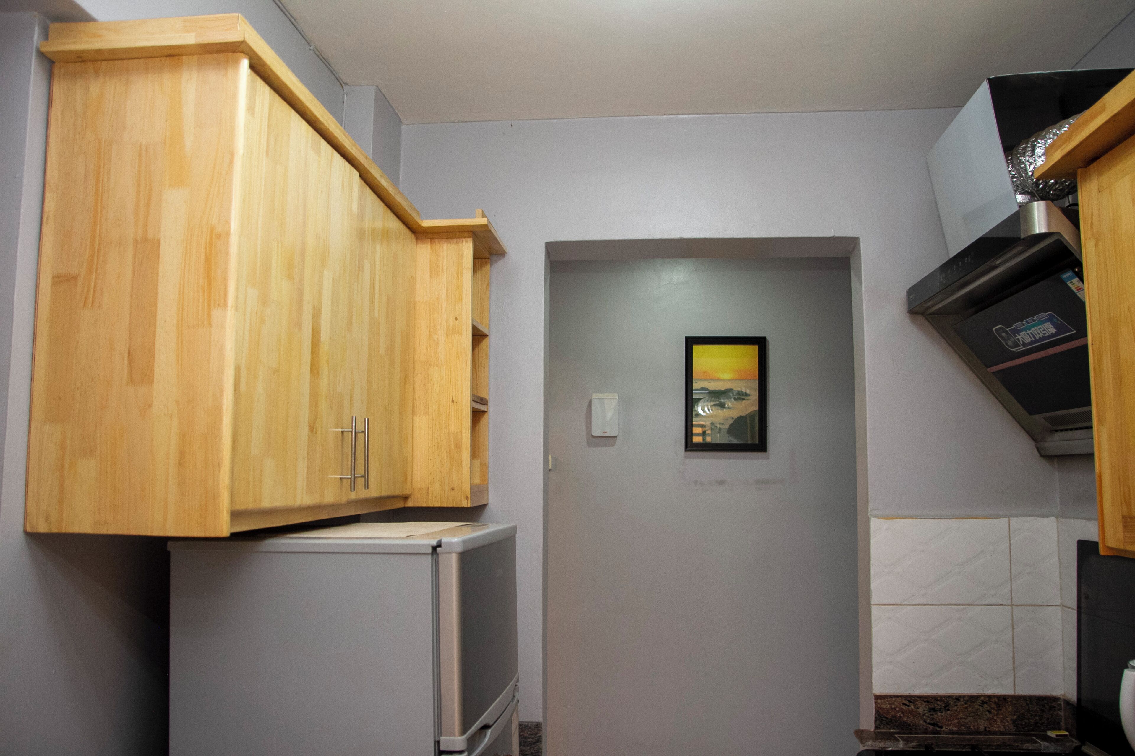 A compact kitchen with wooden cabinets, a built-in microwave, and a stainless steel range hood.