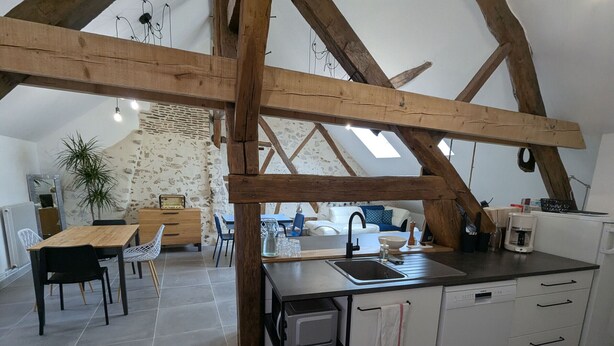 A modern kitchen with exposed wooden beams, a central island with a sink, and a dining area with a table and chairs. - Cozy room in Briare, city center, ideal for cyclists (Briare)