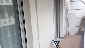 A balcony with a small table and chair, a window, and a tiled floor. - Koukaki Penthouse (Athens)