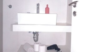 A bathroom with a white sink, a mirror above it, and a toilet paper holder with two rolls. - Koukaki Penthouse (Athens)