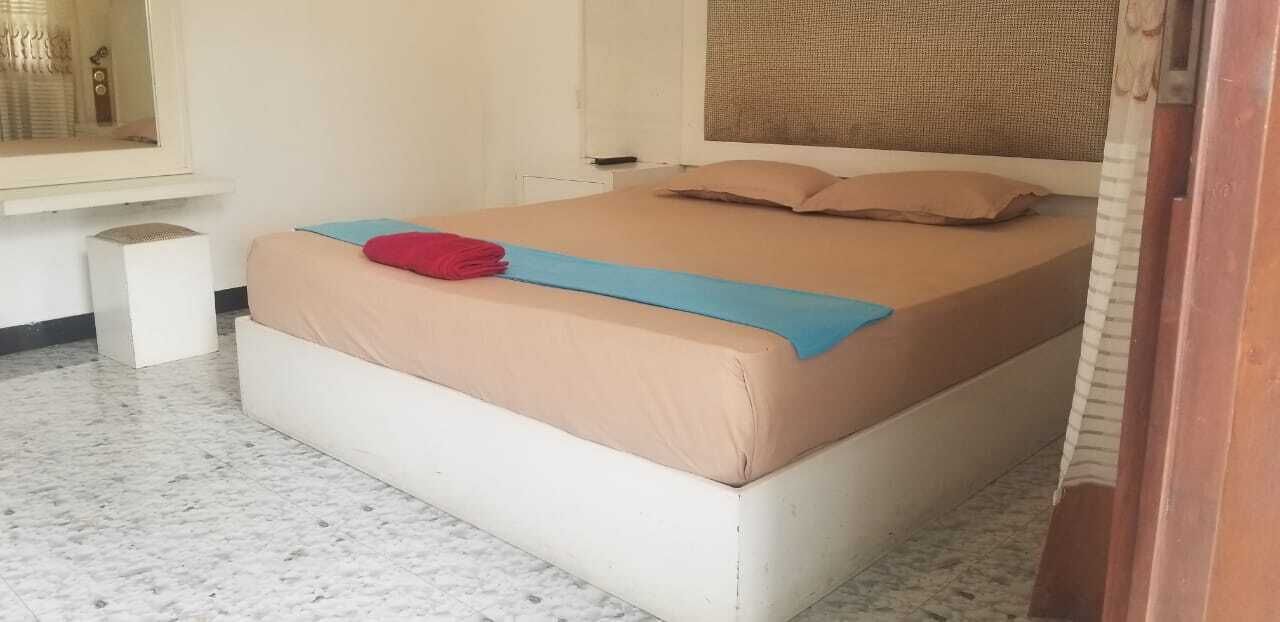 Un dormitorio con una cama, una mesita de noche pequeña y una ventana.