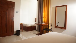 Un dormitorio con cama, escritorio, silla, espejo y puerta.