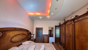 A bedroom with a large bed, wooden headboard, a wardrobe, and a mirror.
