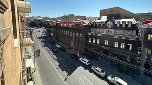 A street view with buildings, vehicles, and a clear sky.