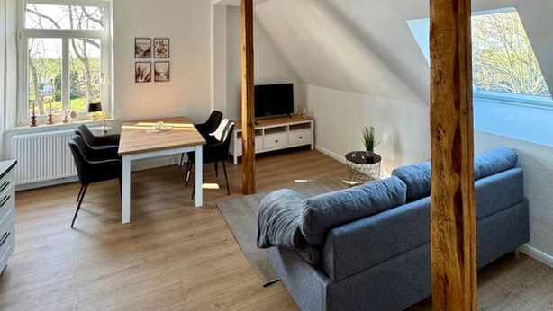 Amplia sala de estar con una mesa de comedor, un sofá gris y un televisor en un espacio loft.