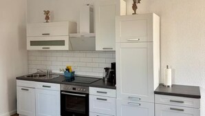 Una cocina moderna con armarios blancos, un lavamanos de acero inoxidable y un horno empotrado.