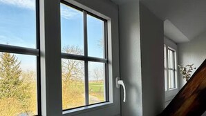 Una habitación con amplios ventanales, un banco blanco y dos velas.