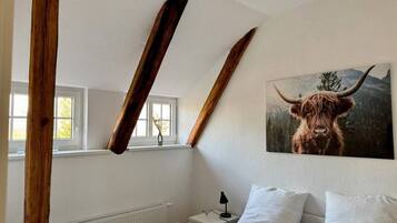 Une chambre à coucher avec un lit, une table de chevet, une lampe et un tableau représentant un taureau.