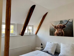 Un dormitorio con una cama, una mesita de noche, una lámpara y un cuadro de un toro.