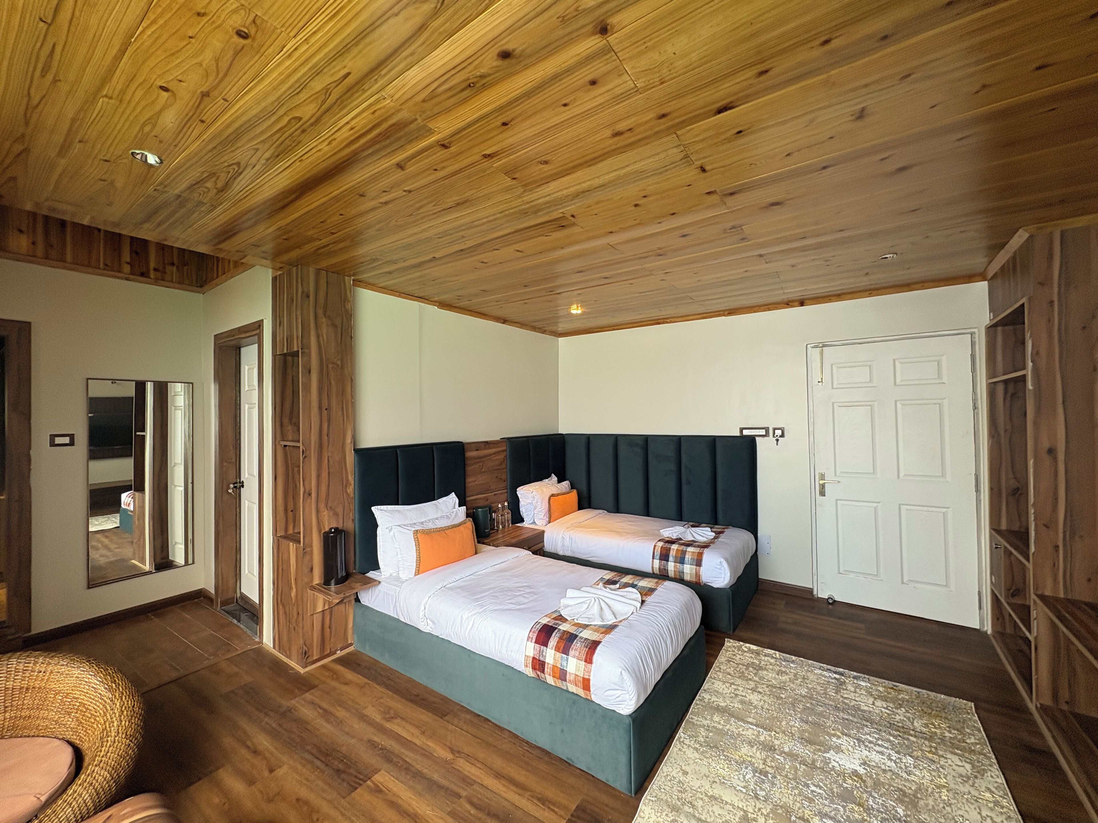 Une chambre avec deux lits, un plafond en bois et un grand miroir.