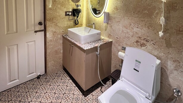 A bathroom with a toilet, sink, and mirror. - Echo Hotel and Spa  (Darjeeling)