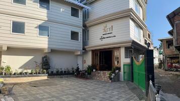 A hotel with a sign reading "Teji Hotel & Spa" and a gated entrance.
