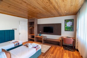A hotel room with two beds, a desk, a chair, a TV, and a wardrobe. - Echo Hotel and Spa  (Darjeeling)