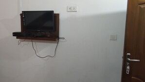 A wall-mounted TV on a wooden shelf with a cable connected to it.