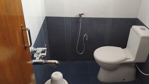 A bathroom with a toilet, shower, and sink.
