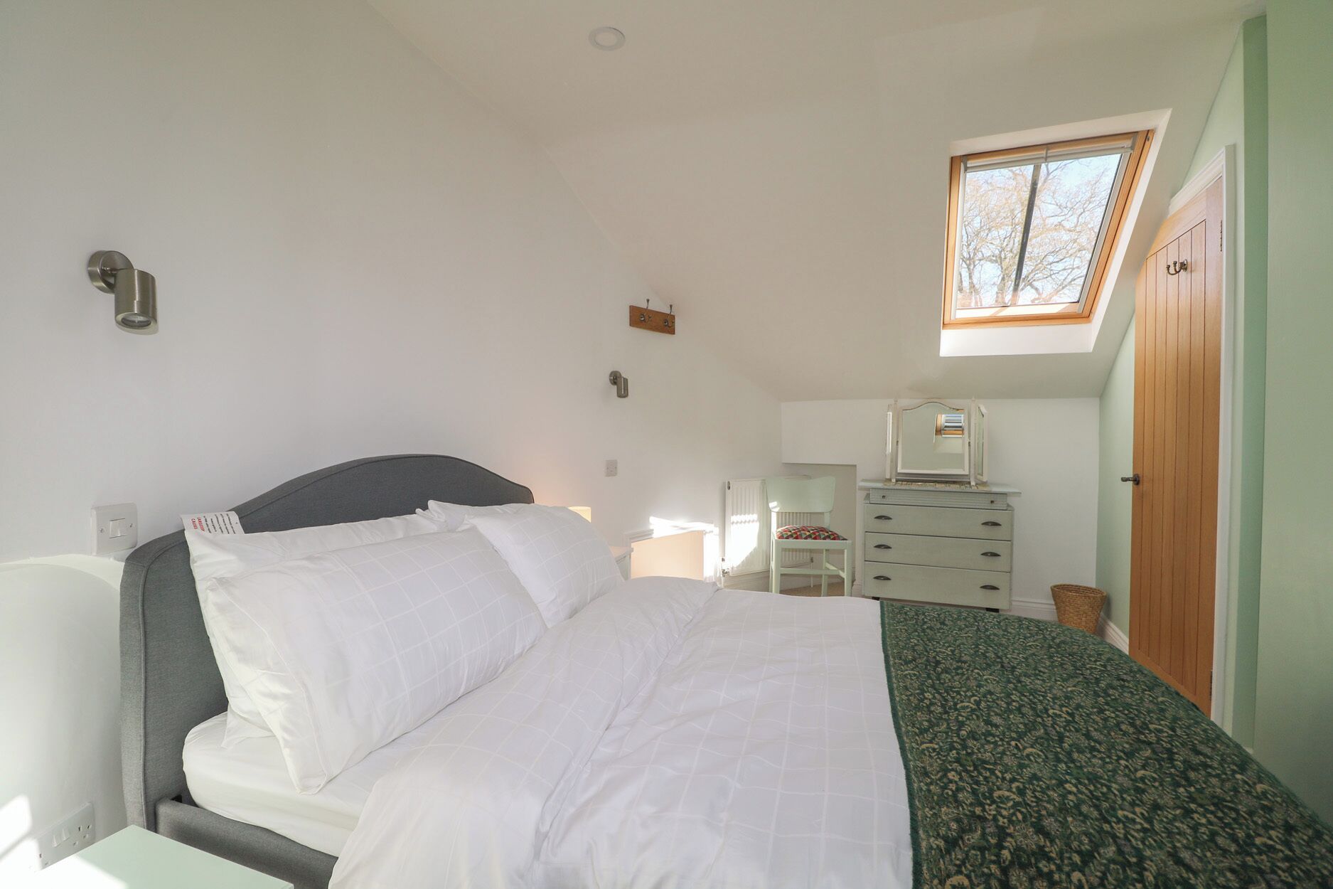 A bedroom with a bed, a dresser, a chair, a desk, and a window.