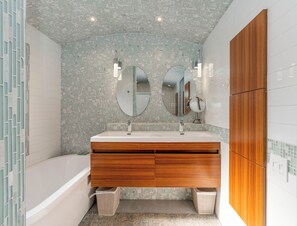 A modern bathroom with a freestanding bathtub, a vanity with a mirror, and a wooden cabinet. - 1BR-Beautiful Ground Floor, Ocean View, Mauna Lani Resort (Kamuela)