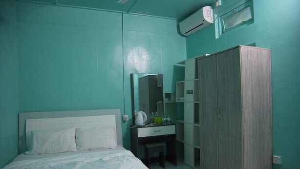 A room with a bed, a desk, a wardrobe, and an air conditioning unit. - WIND STAY Guest House (Malé)