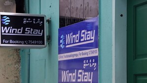 A signboard for 'Wind Stay' with a booking number. - WIND STAY Guest House (Malé)
