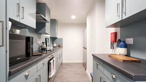 Una cocina moderna con gabinetes grises, horno empotrado y microondas.