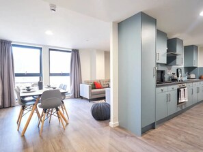 Um apartamento moderno com área de jantar, um sofá e uma cozinha.