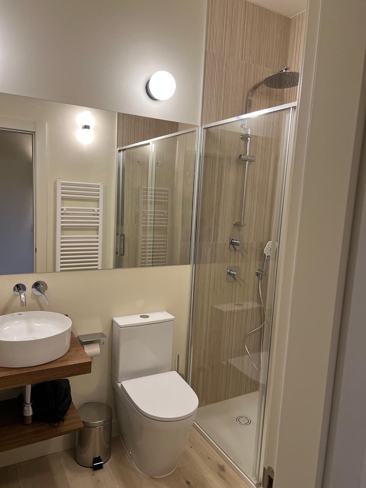 Een moderne badkamer met een douchecabine van glas, een witte wastafel en een toilet.