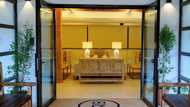 En moderne hotelindgang med træloft, glasdøre og en receptionsdisk.