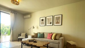 A living room with a sofa, a coffee table, a floor lamp, and a large window with curtains. - FLH Alvor Duo Village Terrace with Pool (Alvor)