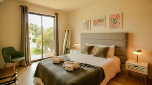 A hotel room with a bed, a chair, a bedside table with a lamp, and a window with curtains. - FLH Alvor Duo Village Terrace with Pool (Alvor)