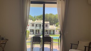 A room with a sliding glass door leading to a pool area, a chair, and a small table. - FLH Alvor Duo Village Terrace with Pool (Alvor)