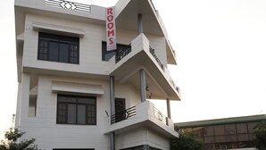 A modern multi-story building with a prominent 'ROOMS' sign. - River View Resort (Haridwar)