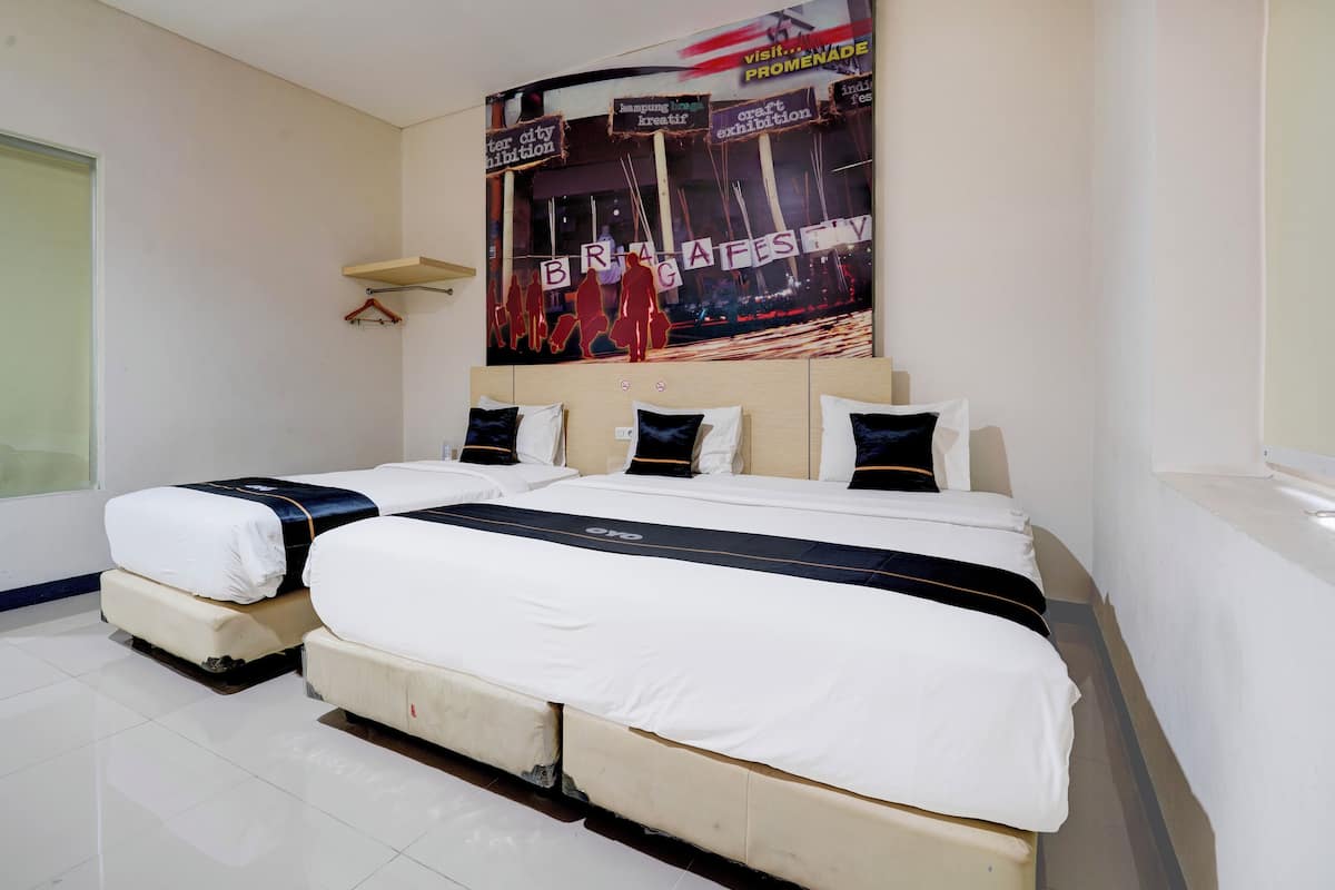 Ein Hotelzimmer mit zwei Betten, einem großen Poster an der Wand und einem kleinen Tisch.