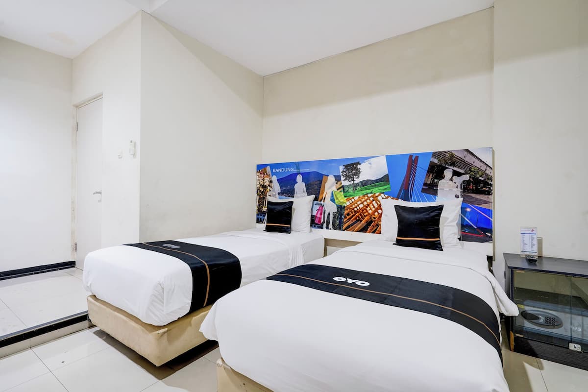 Ein Hotelzimmer mit zwei Betten, einem großen Wandbild, einem kleinen Tisch und einer Glasschrank.