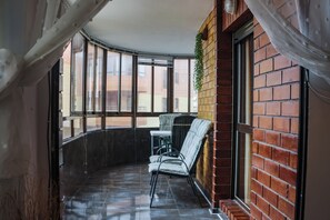 A corner room with a curved window, a brick wall, a hanging plant, and a chair.
